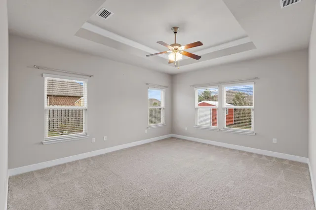 an empty room with chandelier fan and windows
