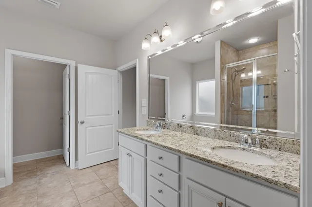 a bathroom with a granite countertop double vanity sink and a mirror