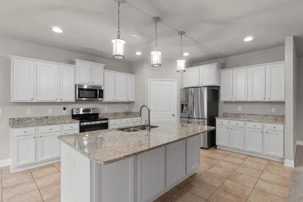 a kitchen with kitchen island granite countertop stainless steel appliances a sink a stove a microwave a center island and cabinets