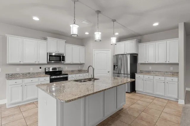 a kitchen with kitchen island granite countertop stainless steel appliances a sink a stove a microwave a center island and cabinets