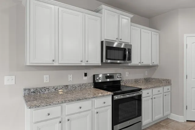 a kitchen with stainless steel appliances granite countertop white cabinets granite counter tops and a hard wood floors