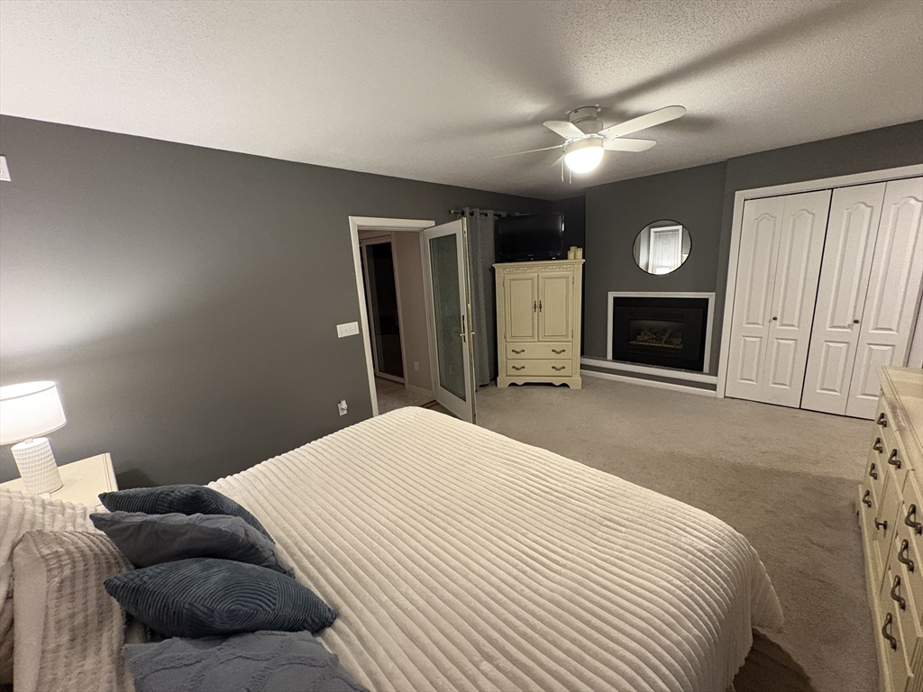 321 Westerly Circle Ludlow, MA 01056 - Photo 31 of 38 a bedroom with a large bed a flat screen tv and a fireplace