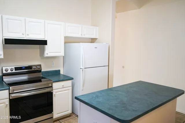 a kitchen with granite countertop a refrigerator sink and stove
