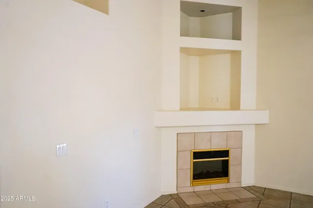 a view of an empty room with window and chandelier fan