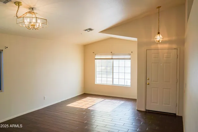 an empty room with wooden floor cabinet and windows