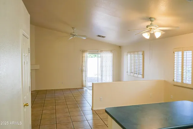 a view of an empty room with window and chandelier fan