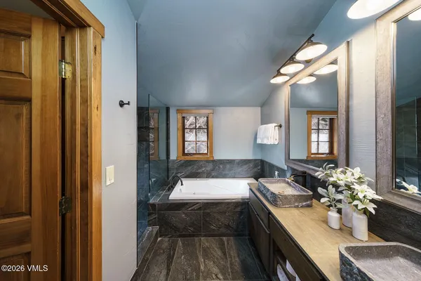 a en suite bathroom with a granite countertop tub and a large mirror