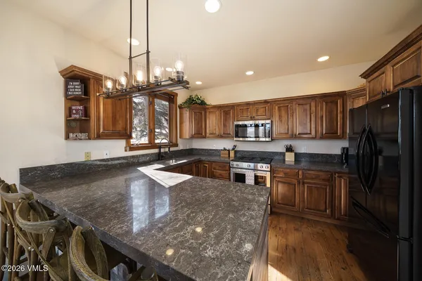 a kitchen with stainless steel appliances granite countertop a sink a stove and a wooden floors