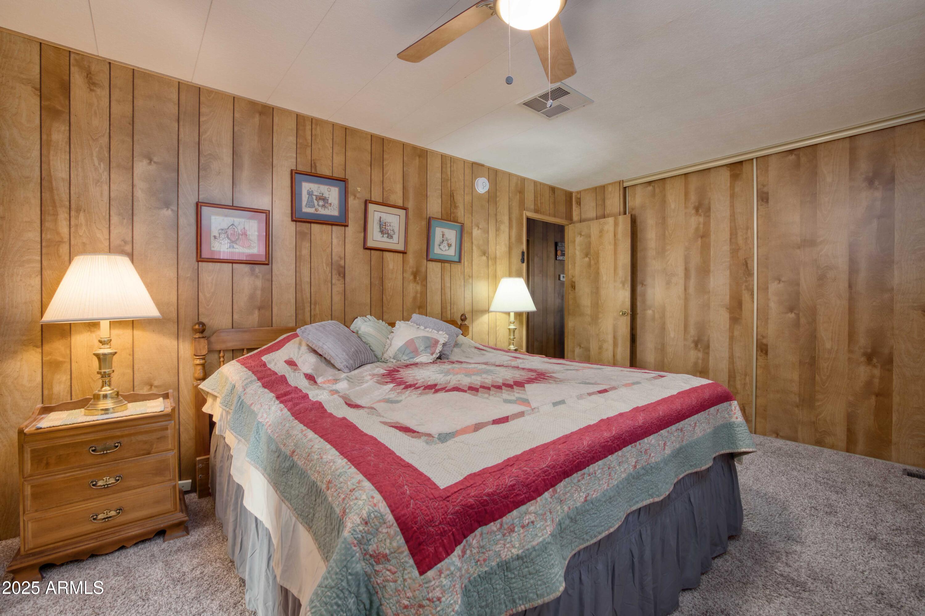 9302 East Broadway Road, Unit 185 Mesa, AZ 85208 - Photo 22 of 24 a spacious bedroom with a bed a dresser and a chandelier