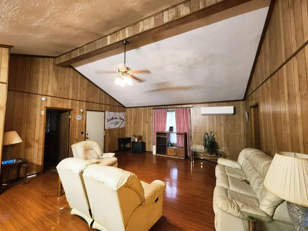 a living room with furniture kitchen view and a wooden floor