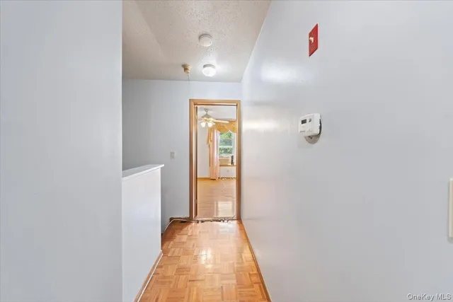 a view of a hallway with wooden floor and a bathroom