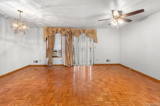a view of an empty room and chandelier fan