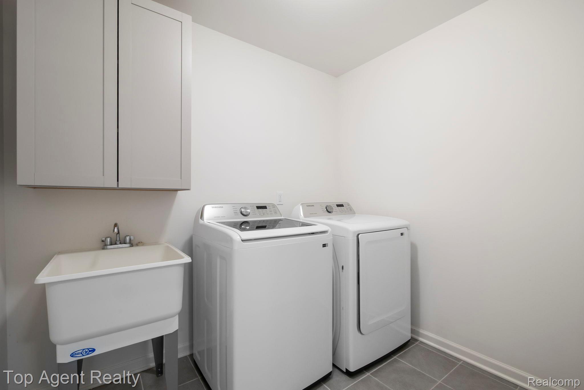 63770 Dequindre Road Washington, MI 48095 - Photo 40 of 61 Laundry room featuring a utility sink with a dual-handle faucet, gray shaker-style upper cabinetry, and gray square floor tiles