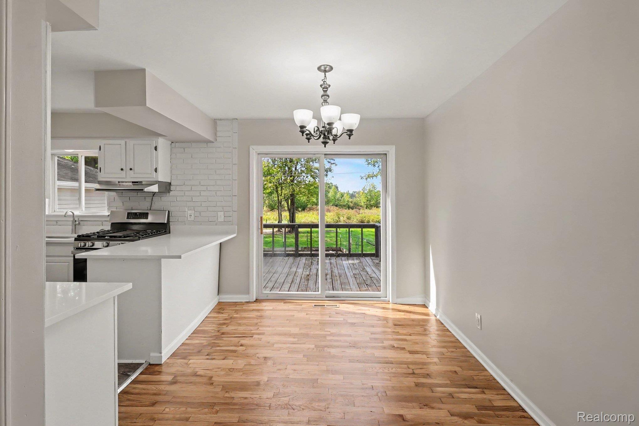 905 North Wilder Road Lapeer, MI 48446 - Photo 7 of 15 Hardwood flooring, sliding glass door, white brick accent wall, white cabinetry, and stainless steel appliances