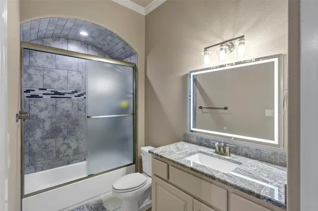 a bathroom with a granite countertop bathtub shower sink vanity and toilet