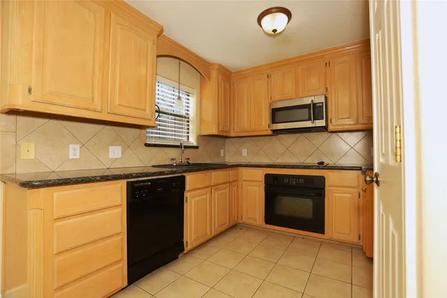 a kitchen with granite countertop a sink stove and microwave