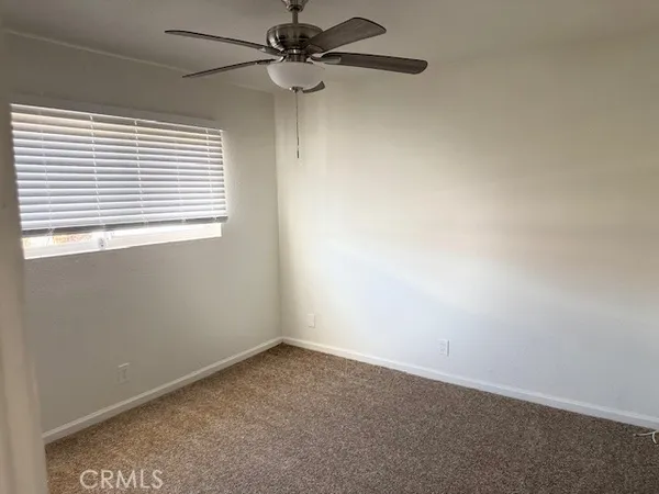 an empty room with a window and a fan