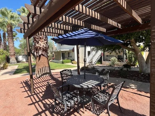 a view of a patio with table and chairs under an umbrella with a small yard