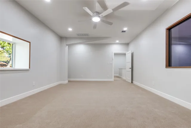en empty room with windows and ceiling fan