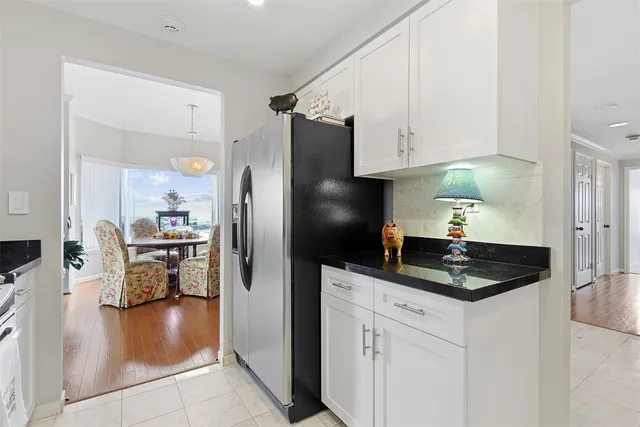 a kitchen with granite countertop a refrigerator a stove a sink and white cabinets