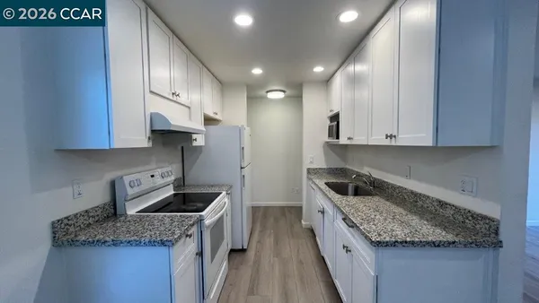 a kitchen with granite countertop a sink a stove and cabinets