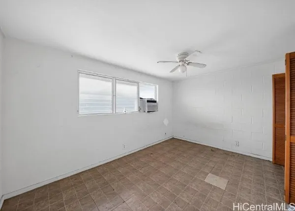 an empty room with a window and a ceiling fan