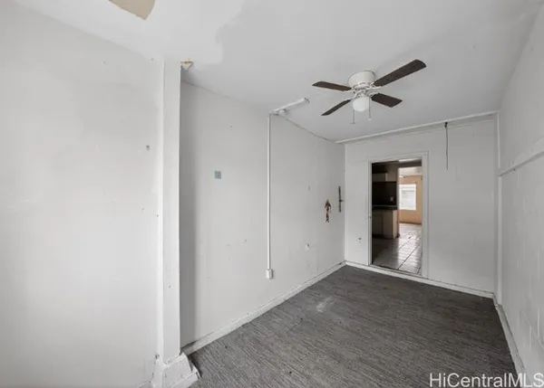 a view of empty room with wooden floor and ceiling fan