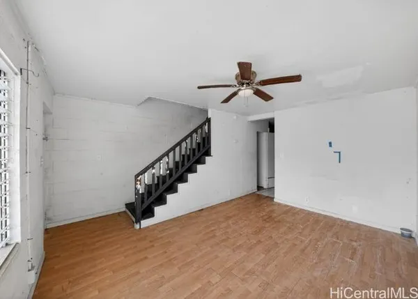 a view of an empty room with wooden floor and stairs