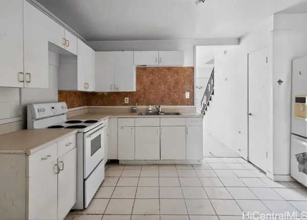 a kitchen with white cabinets a sink stove and refrigerator