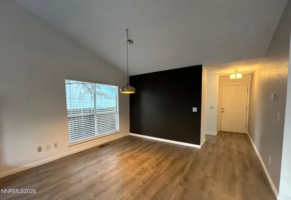 an empty room with wooden floor cabinet and windows