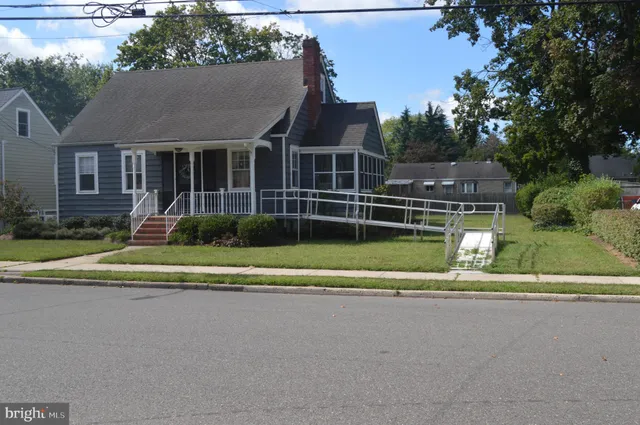 a view of a house in a big yard with plants and large trees