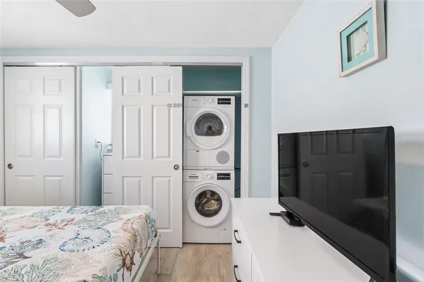 a bedroom with a bed and a washing machine with wooden floor