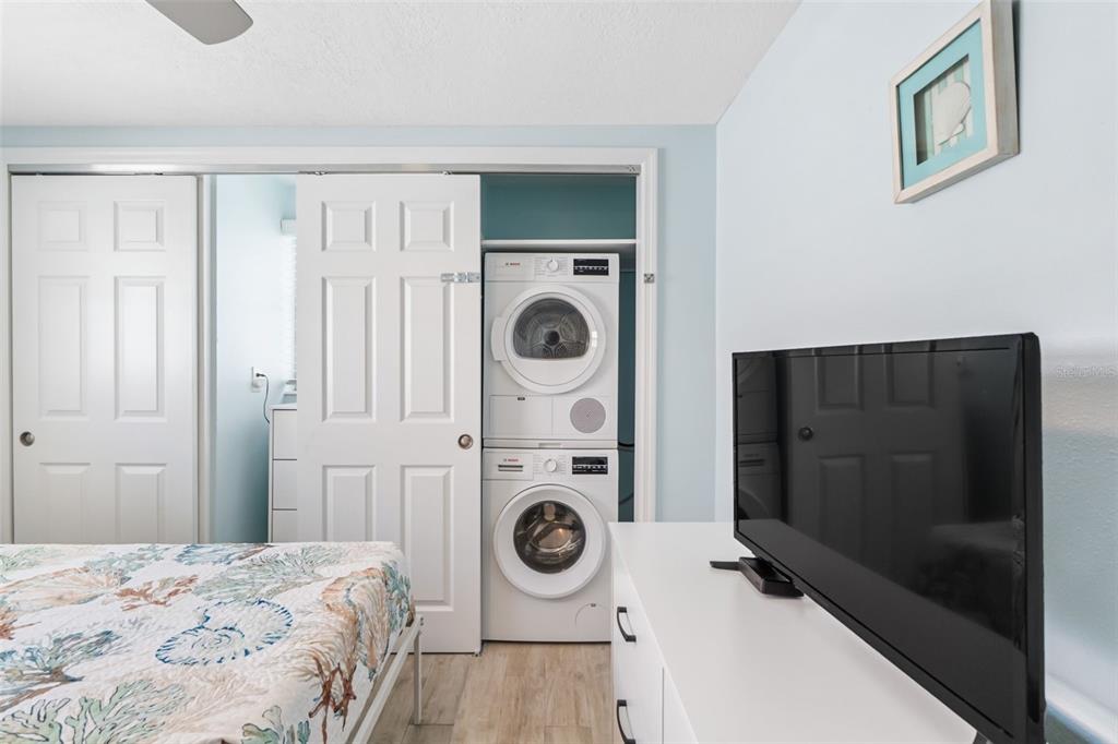 6154 Midnight Pass Road, Unit A05 Sarasota, FL 34242 - Photo 19 of 39 a bedroom with a bed and a washing machine with wooden floor
