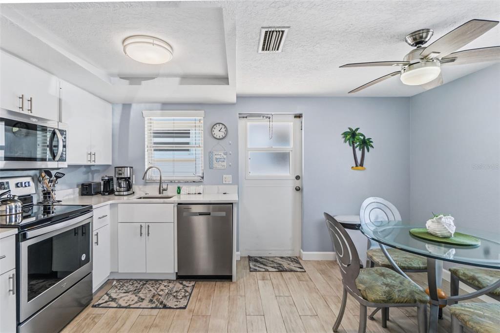 6154 Midnight Pass Road, Unit A05 Sarasota, FL 34242 - Photo 2 of 39 a kitchen with stainless steel appliances a white table chairs and a refrigerator