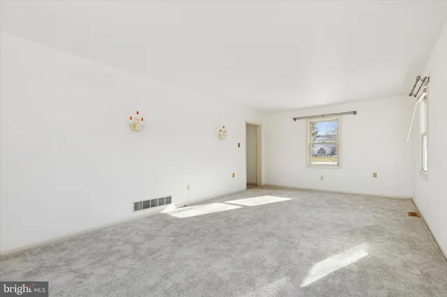 an empty room with white wall and windows