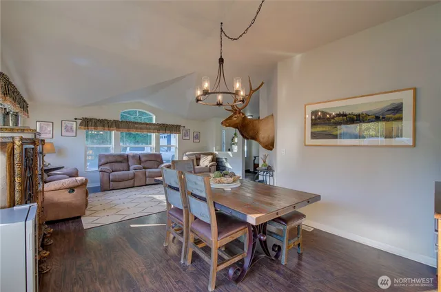 a dining room with wooden floor a chandelier a wooden table and chairs