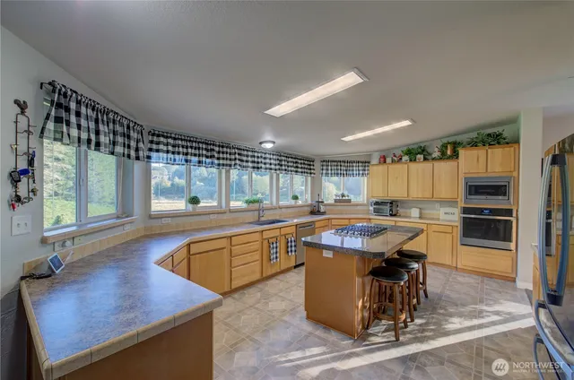 a dining hall with stainless steel appliances granite countertop a sink a counter space and chairs