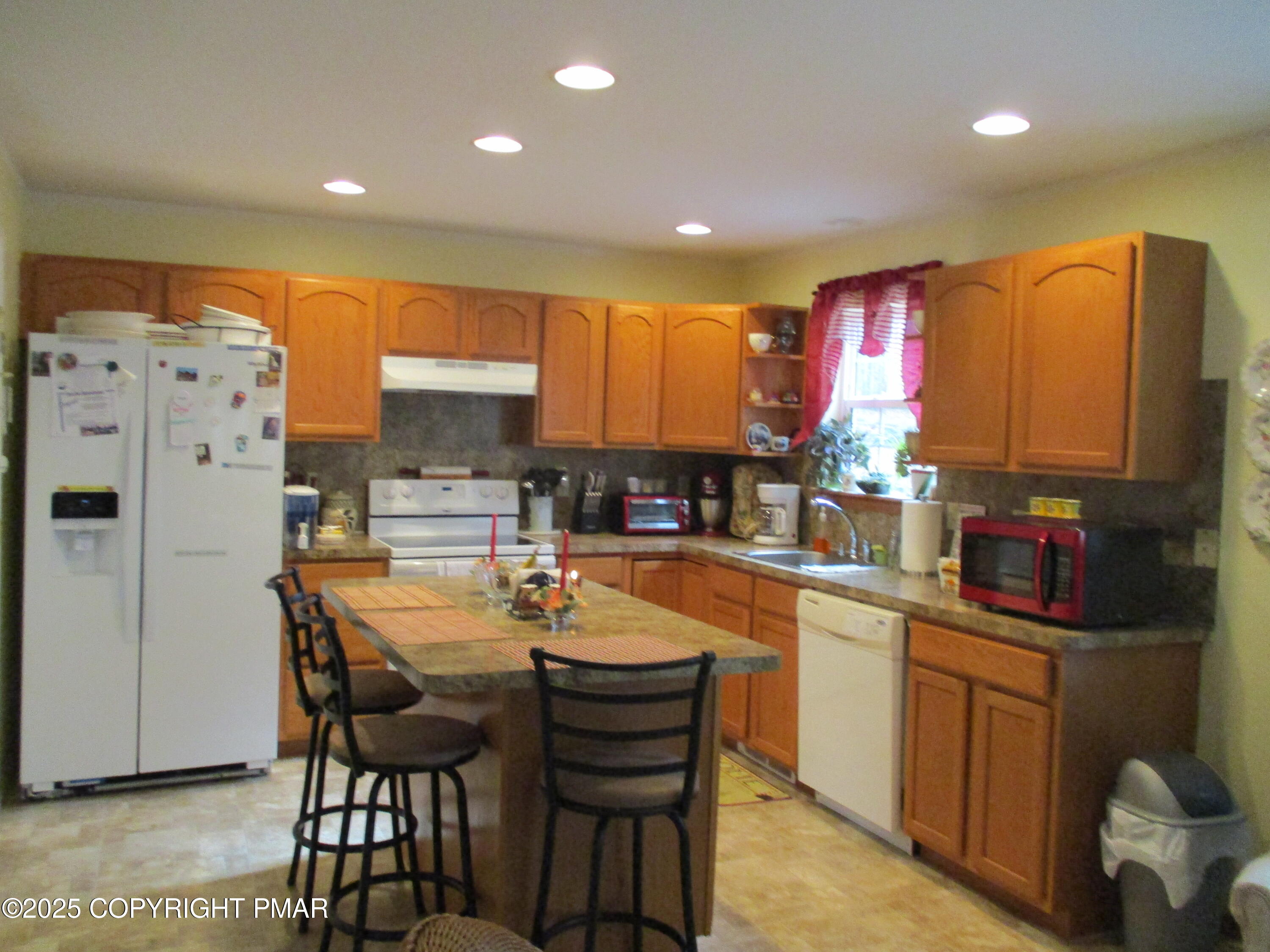 3290 Bluebird Drive Bushkill, PA 18324 - Photo 4 of 19 a kitchen with granite countertop a refrigerator oven a sink dishwasher and white cabinets with wooden floor