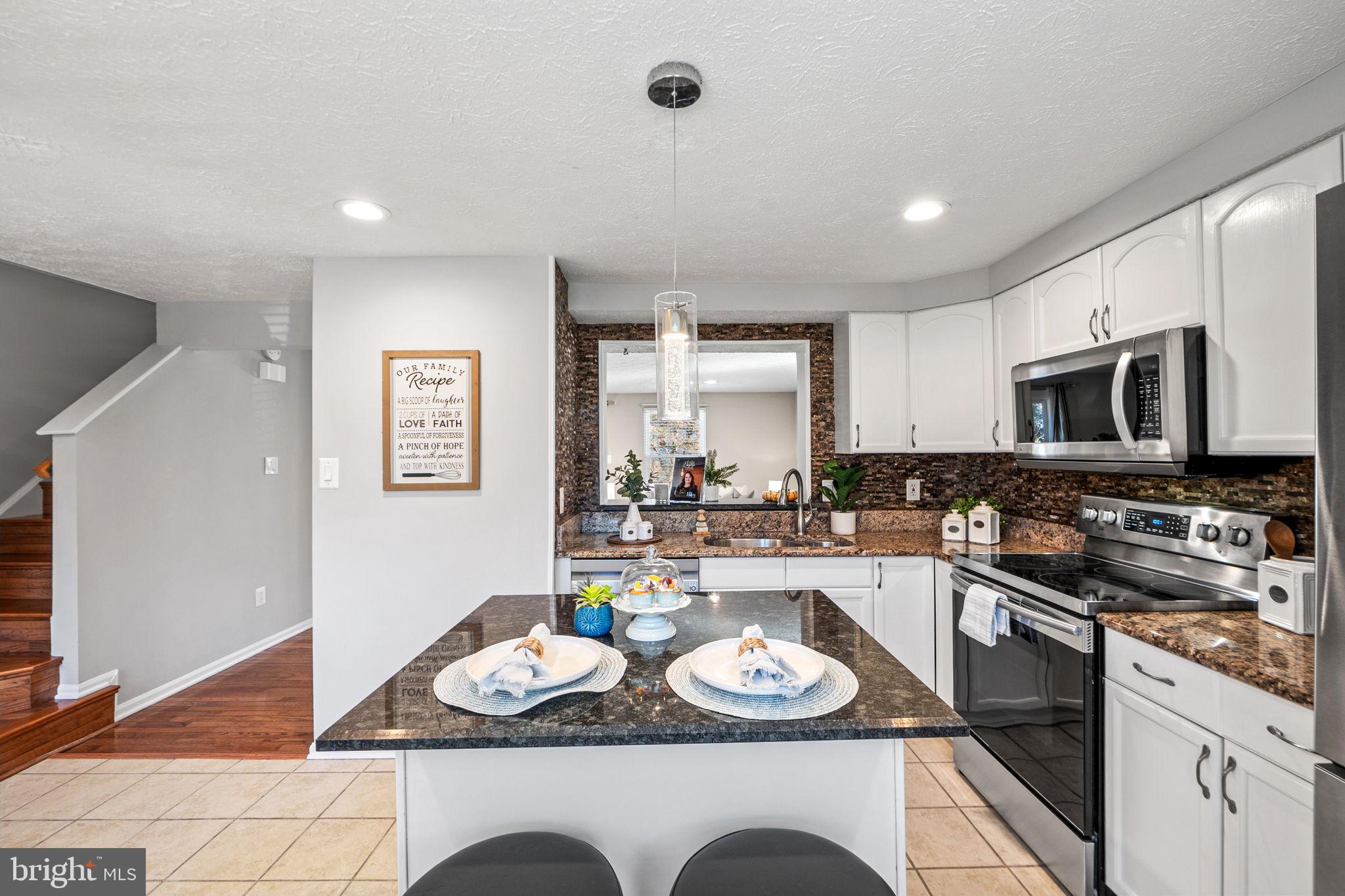 1747 Sundance Drive Reston, VA 20194 - Photo 3 of 36 a kitchen with stainless steel appliances granite countertop a sink a stove a microwave a counter top space and cabinets