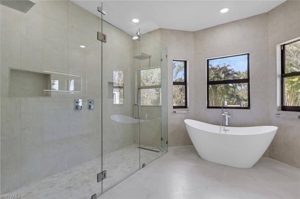 730 29th Street Southwest Naples, FL 34117 - Photo 31 of 50 Full bath with double vanity, a soaking tub, tile walls, and light marble finish flooring