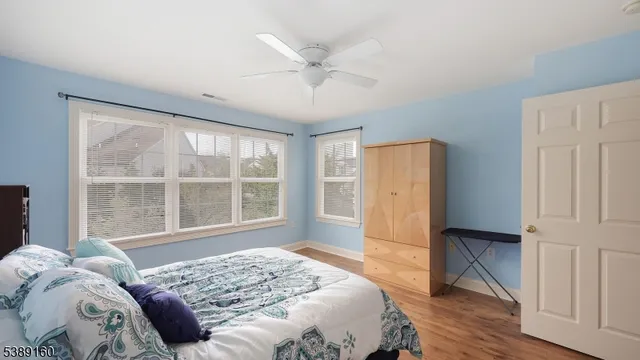 a bedroom with a bed and a large window with wooden floor