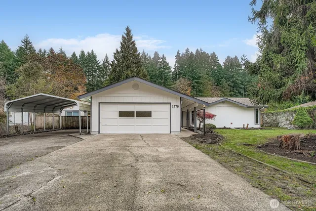 a view of a house with a yard and large trees