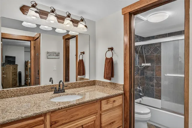 a bathroom with a granite countertop sink a toilet and a mirror