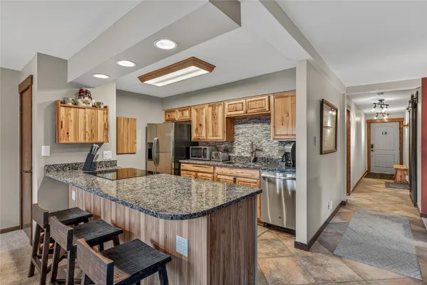 a kitchen with kitchen island granite countertop a table chairs refrigerator and sink