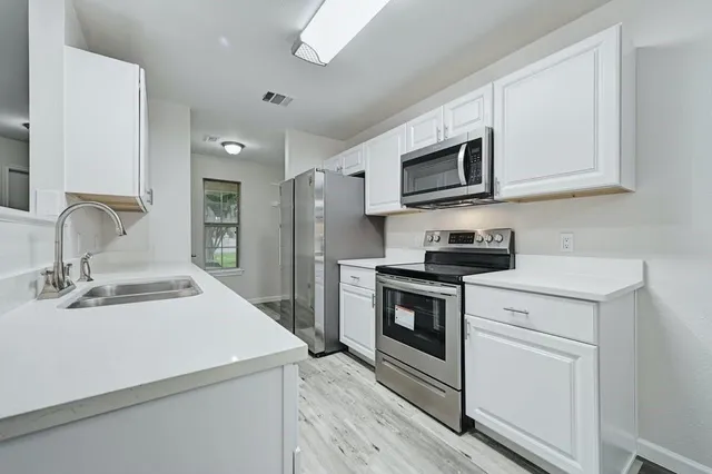 a kitchen with stainless steel appliances a stove microwave and sink