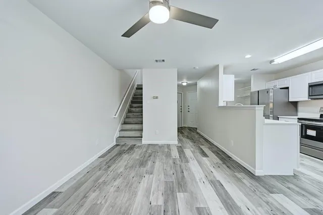 a view of a kitchen with wooden floor electronic appliances and stairs