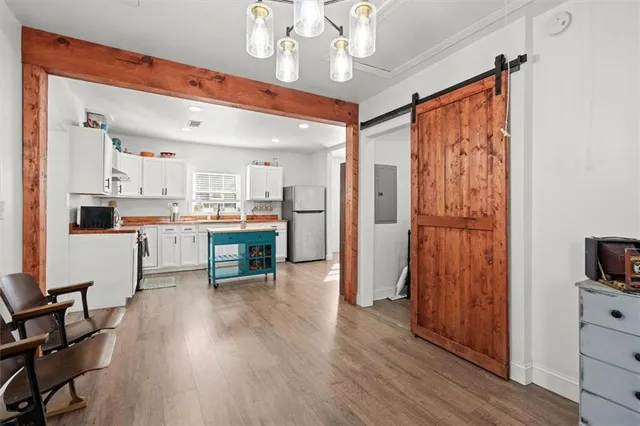 a kitchen with stainless steel appliances a sink a stove a refrigerator cabinets and a dining table with wooden floor