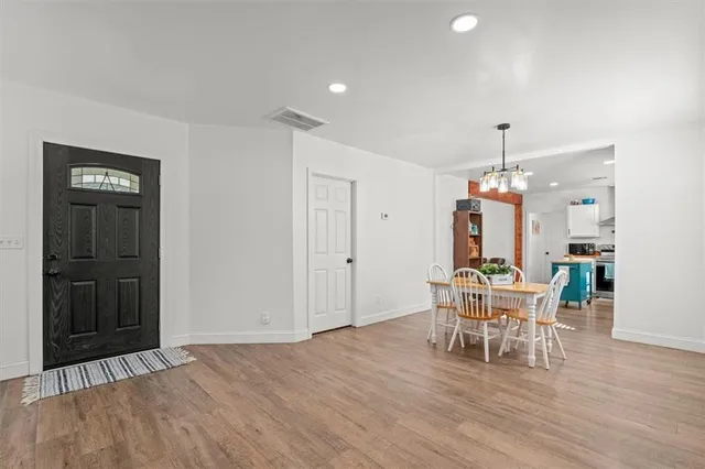 a dining room with wooden floor a chandelier a wooden table and chairs