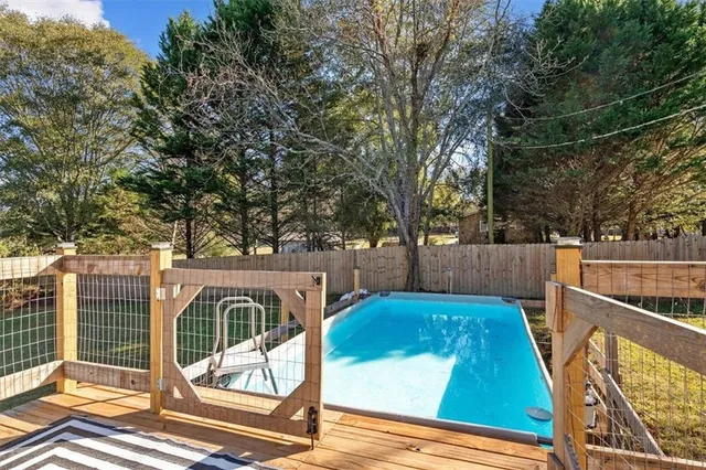 a view of backyard with large trees and wooden fence