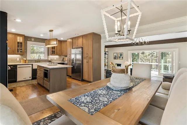 a kitchen with stainless steel appliances granite countertop a sink dishwasher stove top oven a dining table and chairs with wooden floor